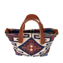 Load image into Gallery viewer, Overhead view of women's southwestern mini tote handbag. Chestnut brown leather handles. Antique brass hardware on sides of purse to attach a strap. Interior magnetic closure.