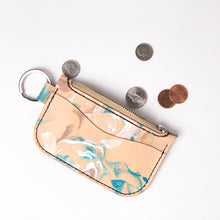 Load image into Gallery viewer, Front view of leather key chain zipper wallet with one front pocket, zipper pocket and a shiny nickel key ring attached. Zipper open with coin change next to open zipper pocket. Leather is a light natural color painted with water colors: brown, turquoise and and pearlescent white dyes. Dark brown thread.