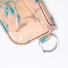 Load image into Gallery viewer, Close up of leather key chain zipper wallet with one front pocket, zipper pocket and a shiny nickel key ring attached. Leather is a light natural color painted with water colors: brown, turquoise and and pearlescent white dyes. Dark brown thread.